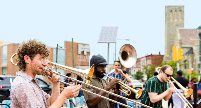 A brass band playing music on the corner of 50th and Baltimore