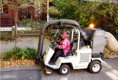 University City clean team member operating a street cleaning machine to pick up leaves