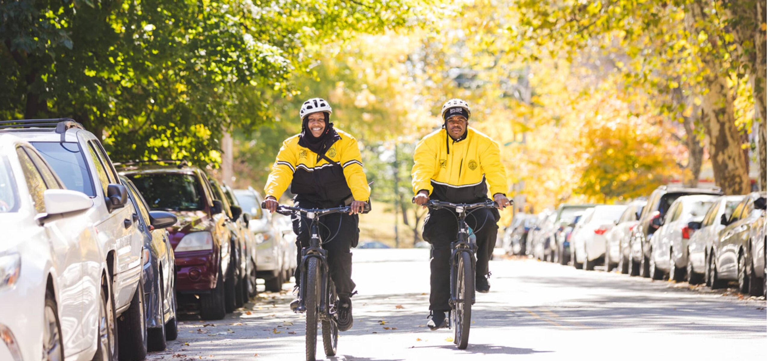 Two safety ambassadors ride their bikes on a sunny, fall day