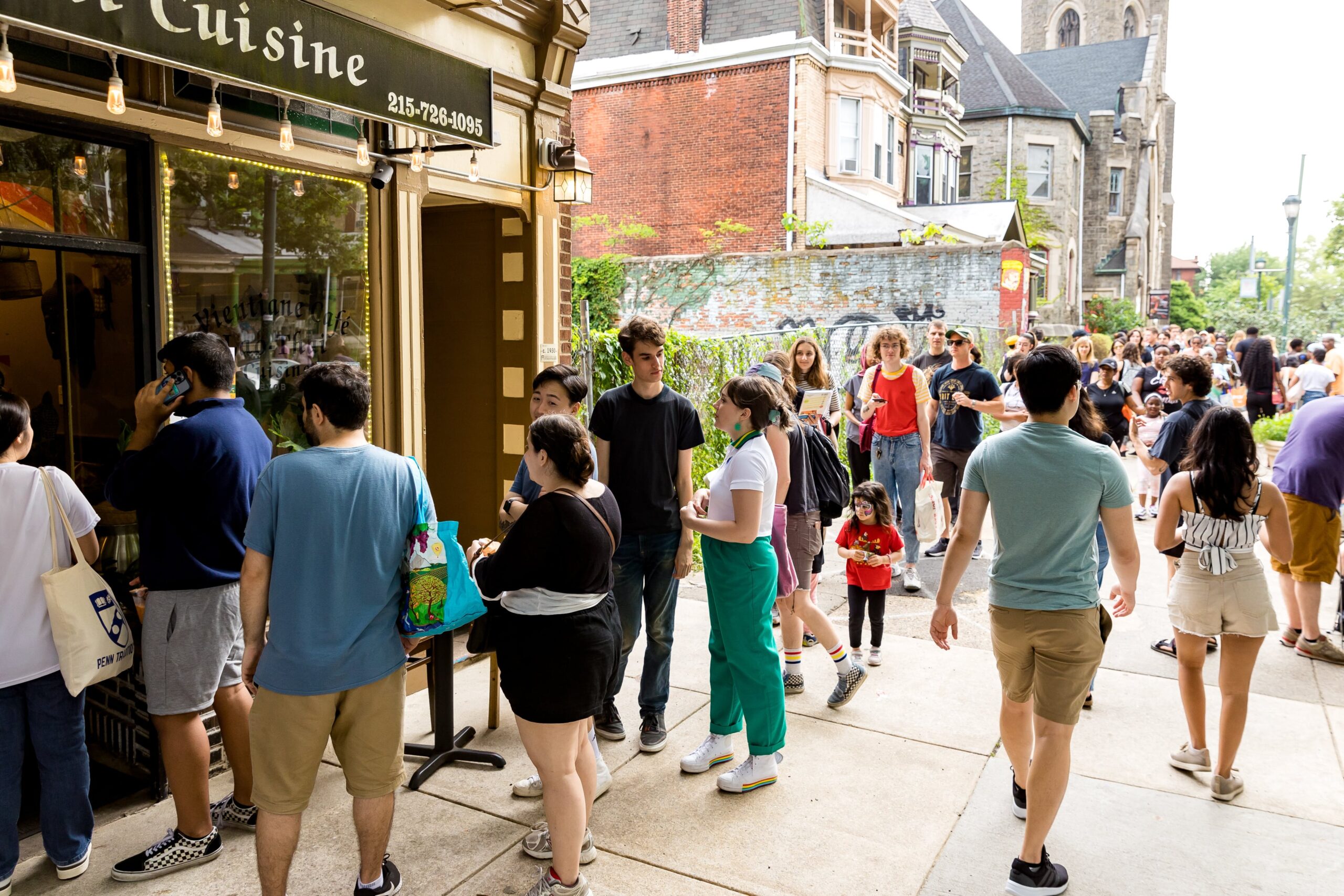 A lively crowd lines up outside a local business during the Baltimore Avenue Dollar Stroll, showcasing the energy of this popular community event.