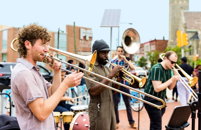 A brass band plays outside on the corner of 50th and Baltimore.