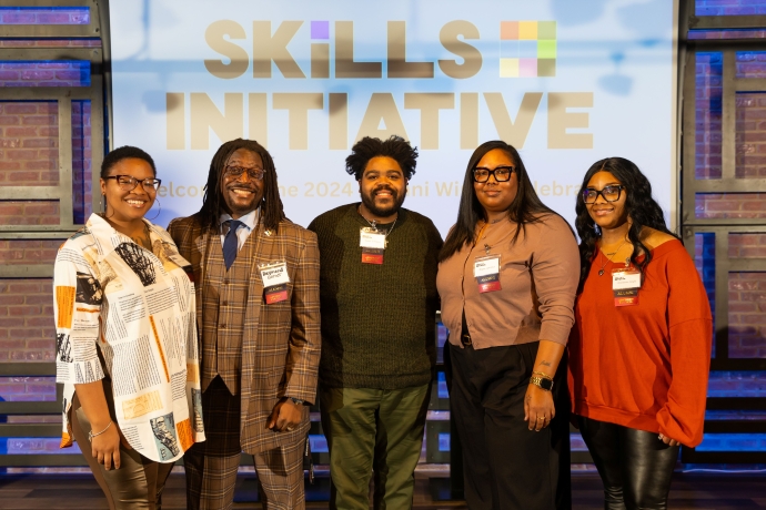 Group of five smiling people in front of a "Skills Initiative" sign