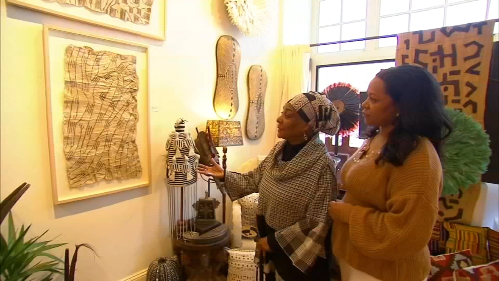 Two women stand looking at art in an Afro-centric art gallery