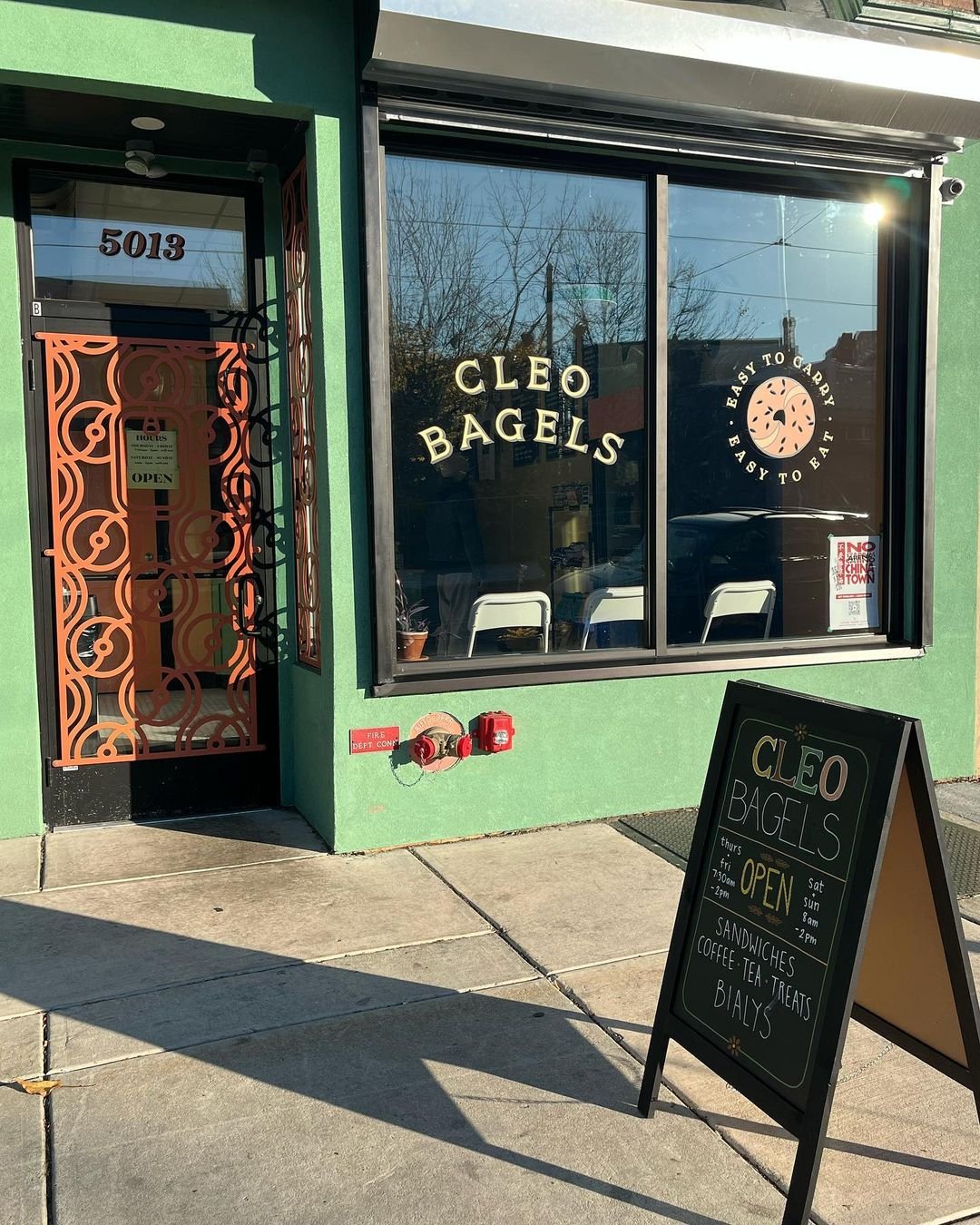 Green storefront with the text "Cleo Bagels" and a graphic image of a bagel printed on the front window