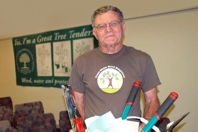 Community member Mike Hardy holds a bucket of tree care tools