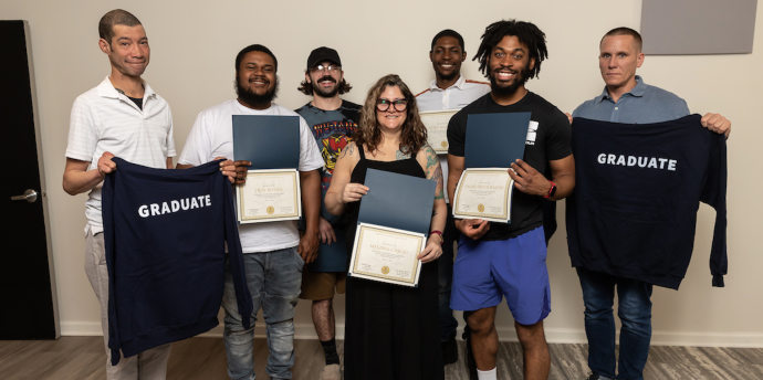 Skills Initiative graduates hold up t-shirts at their graduation ceremony.