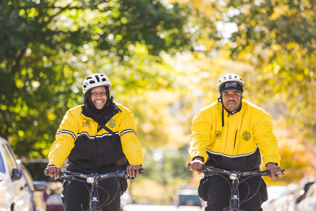 Two UCD Safety Ambassadors biking through the neighborhood on patrol