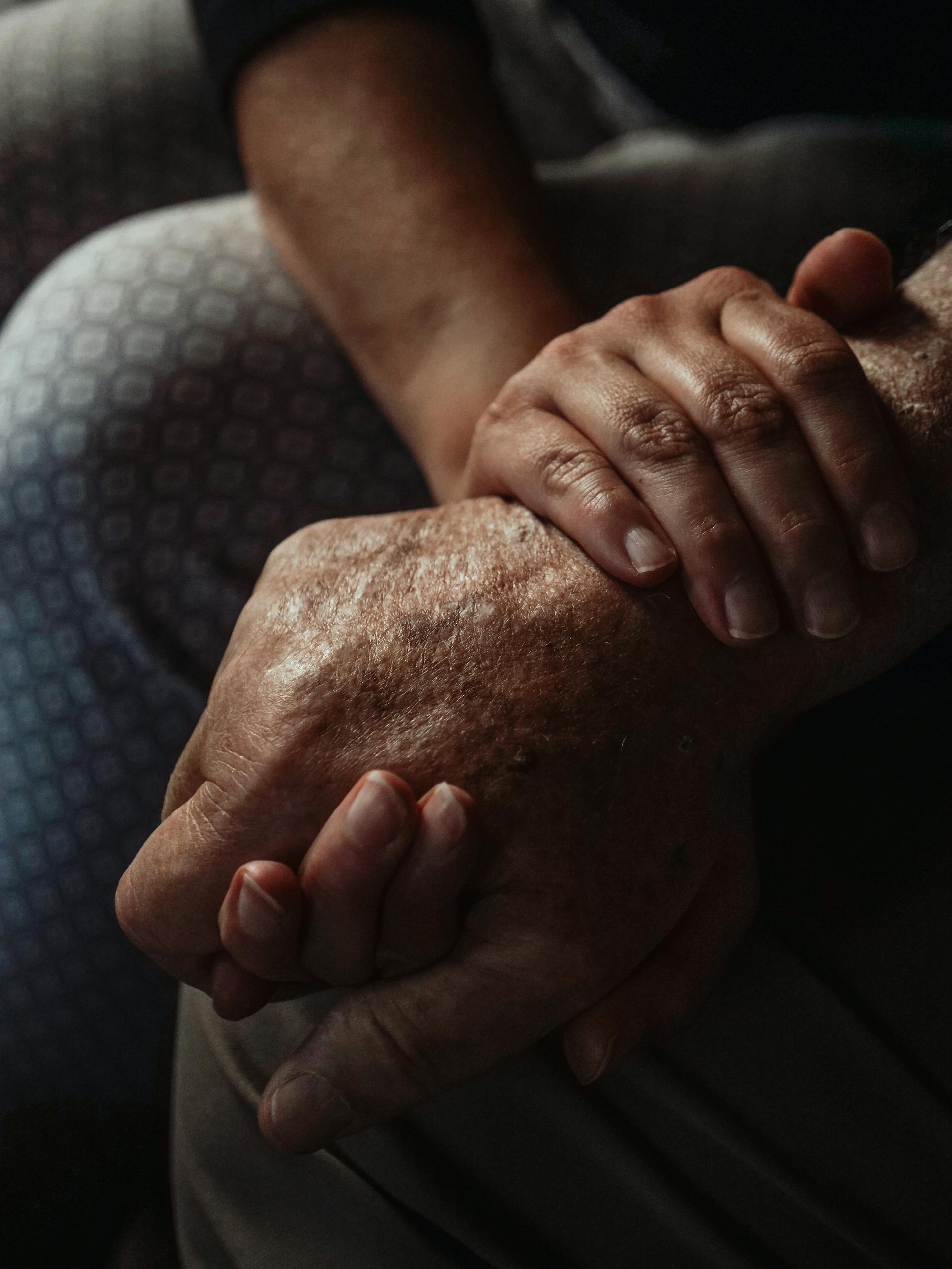 a moody photo of two people holding hands. The mood is somber