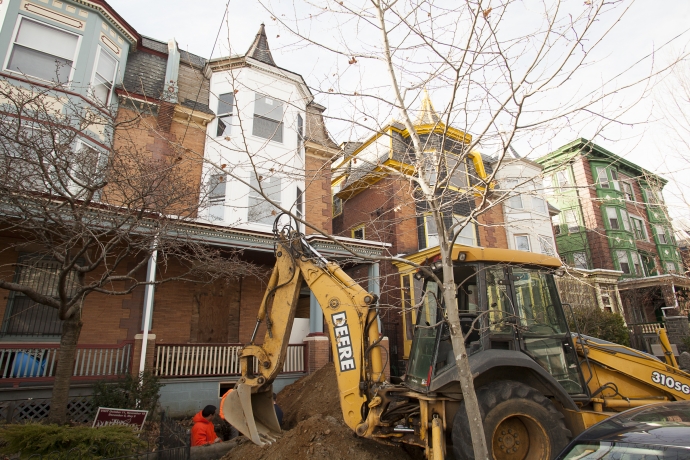 A bulldozer stands outside a line of row homes in West Philadelphia